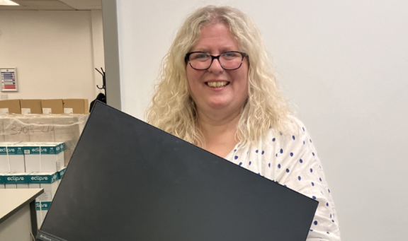 Caroline holds a computer monitor