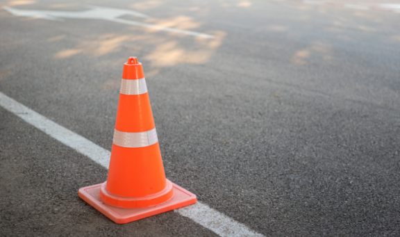 Orange and white traffic cone on tarmac with road markings