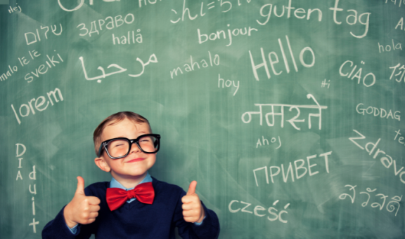 Child standing in front of a blackboard covered with words in foreign languages