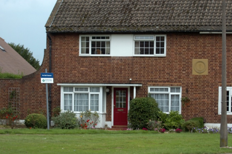 End of terrace house with a red door.