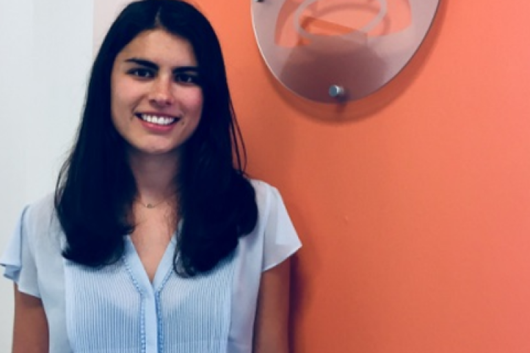 Katie George smiling in front of an orange wall