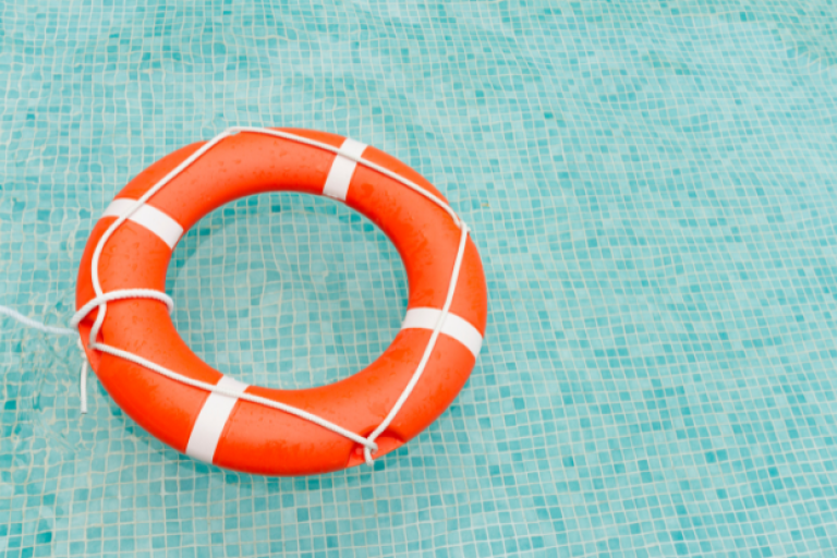 An orange rescue ring floating in a pool.