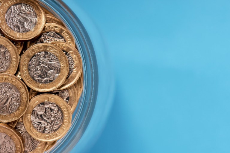 A dish of pound coins against a light blue background