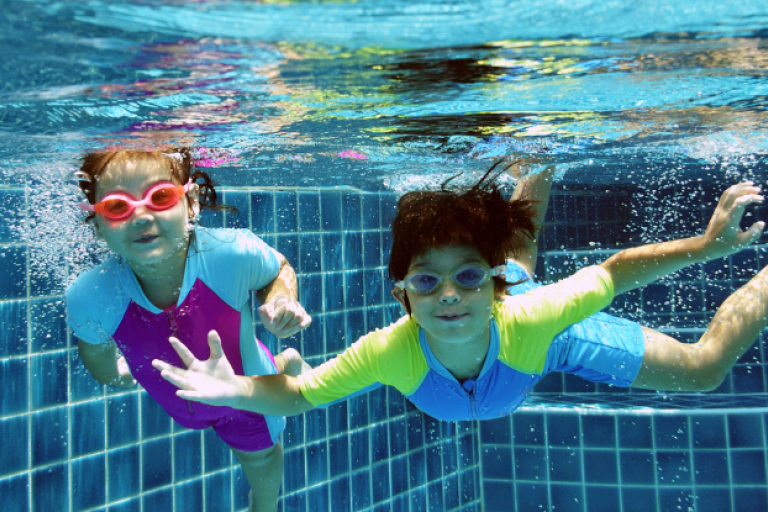 Children swimming underwater in swimming pool