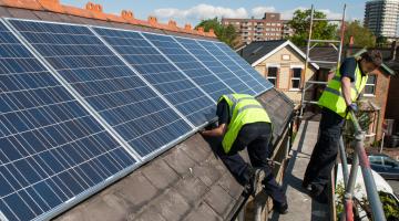 Two men on a roof installing solar panels
