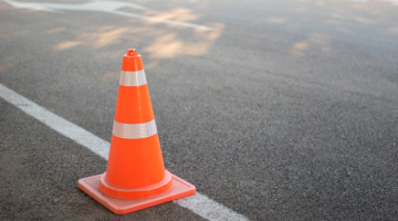 Orange and white traffic cone on tarmac with road markings