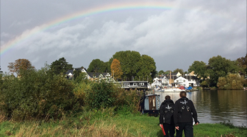 Officers by the river with a rainbow behind