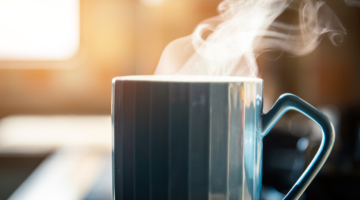 Mug with steam flowing out the top on a kitchen side