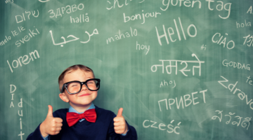 Child standing in front of a blackboard covered with words in foreign languages