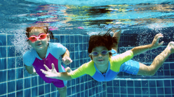 Children swimming underwater in swimming pool